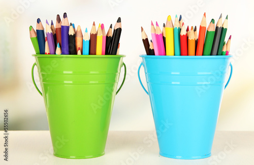 Color buckets with multicolor pencils, on color background