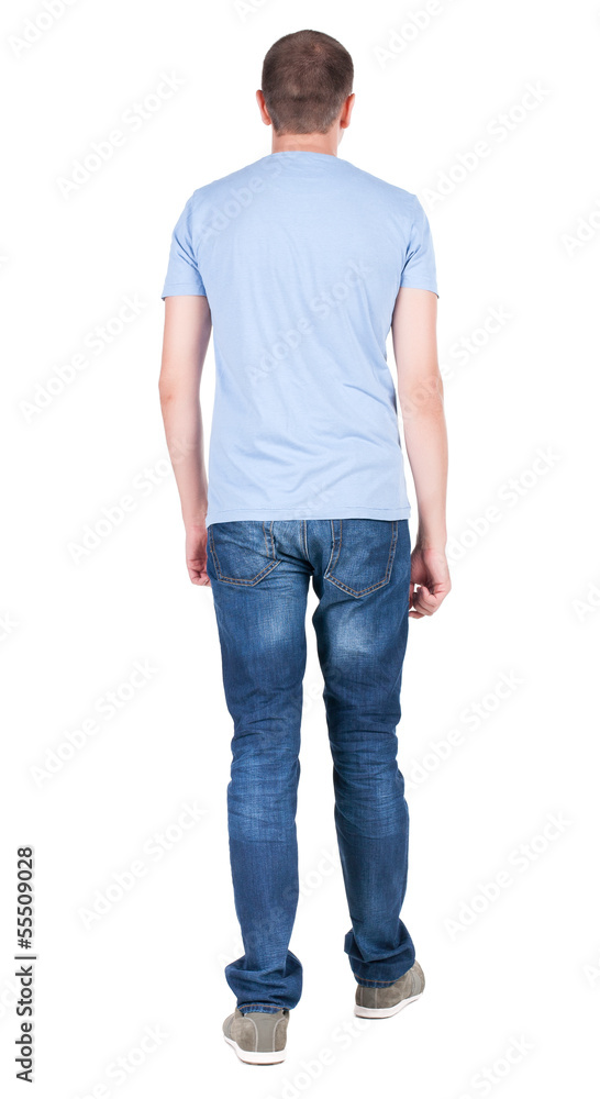 Back view of young man in t-shirt and jeans looking. guy standi Back view of young man in t-shirt and jeans looking. guy standi