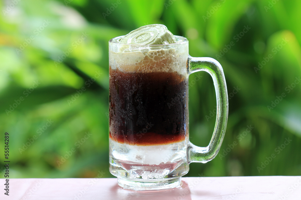 Root beer float, a tasty summer treat.on Green tree background Root beer float, a tasty summer treat.on Green tree background