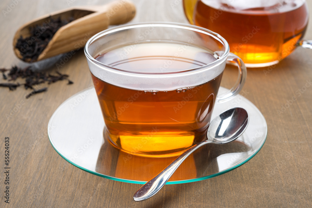 Transparent cup of black tea and teapot on wooden background Transparent cup of black tea and teapot on wooden background