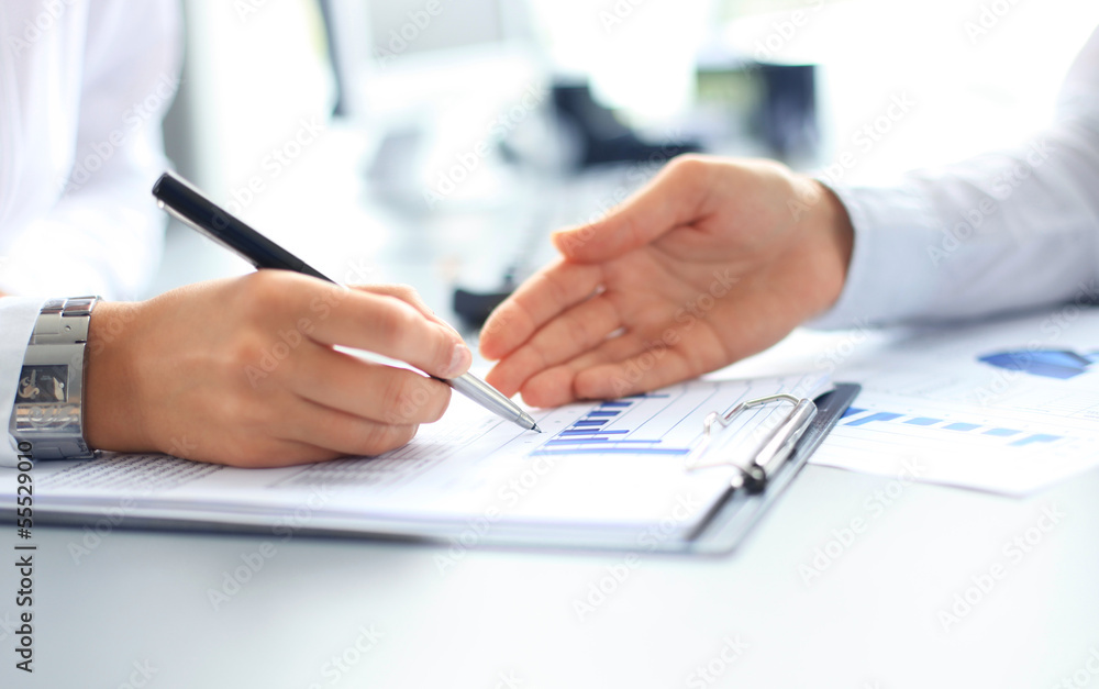 Unrecognizable business person analyzing graphs and taking notes Unrecognizable business person analyzing graphs and taking notes
