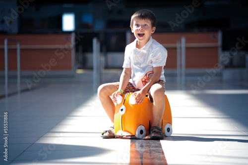 Cute little boy with orange suitcase at airport