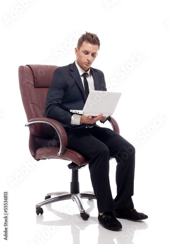 Handsome businessman sitting in chair with laptop