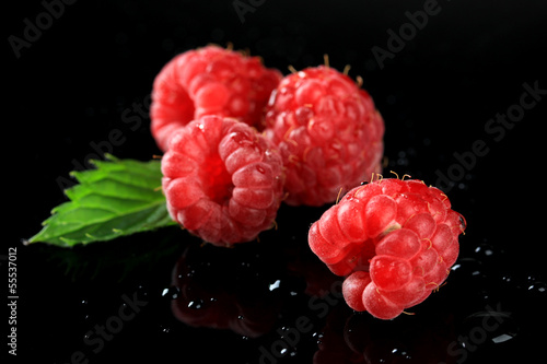 Ripe sweet raspberries with drops on dark background