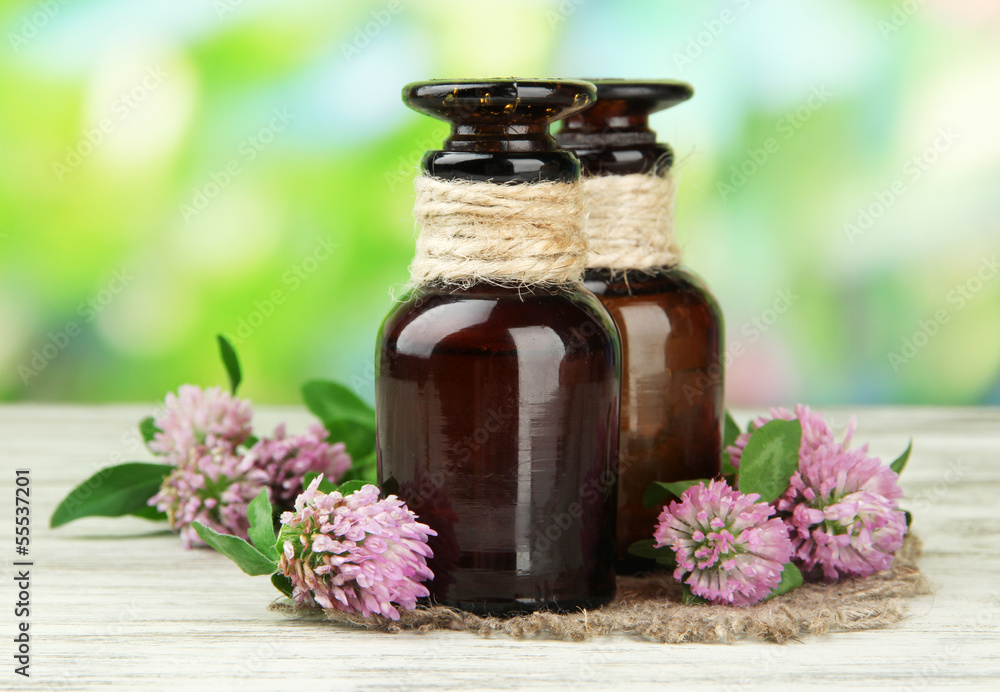 Naklejka Medicine bottles with clover flowers on wooden table, outdoors
