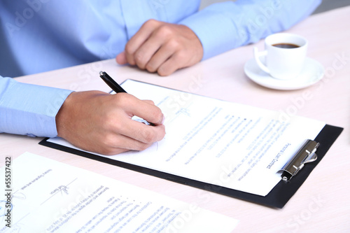 Businessman writing on document in office close-up