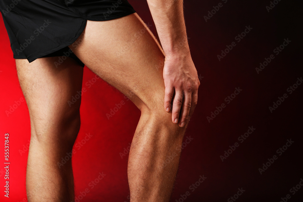Young man with knee pain, on red background Young man with knee pain, on red background