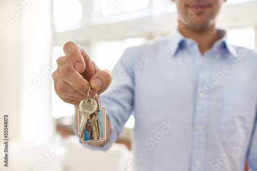 A man holds in his hand the keys of his house, indoor.