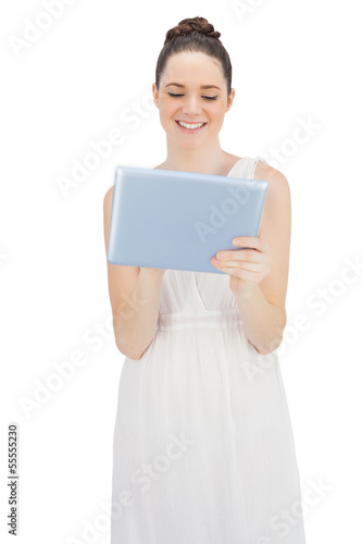 Smiling young model in white dress using tablet computer