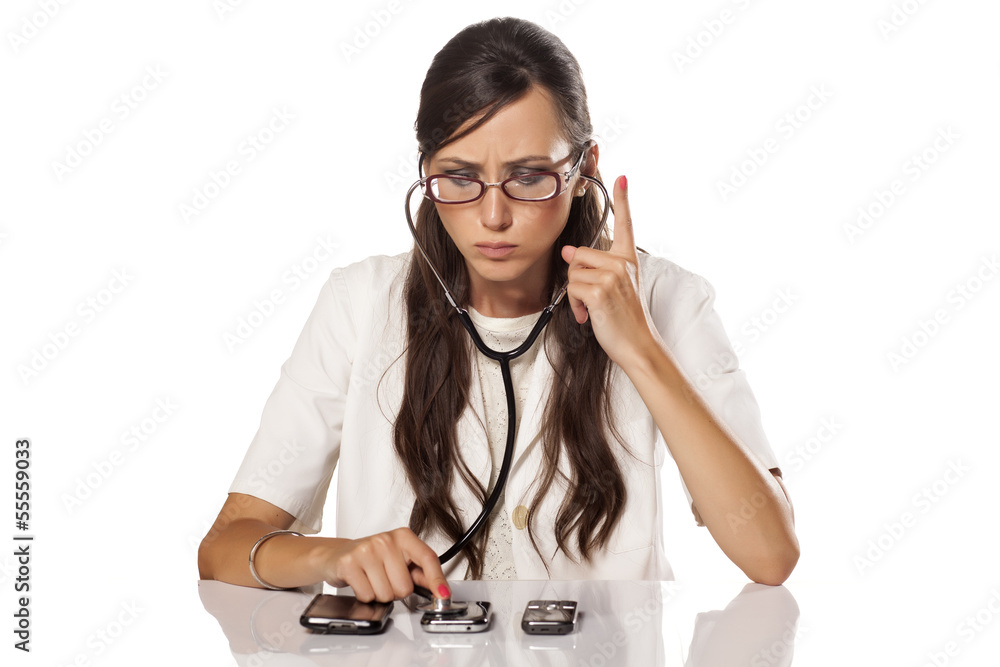 concentrated doctor examines phones using a stethoscope concentrated doctor examines phones using a stethoscope