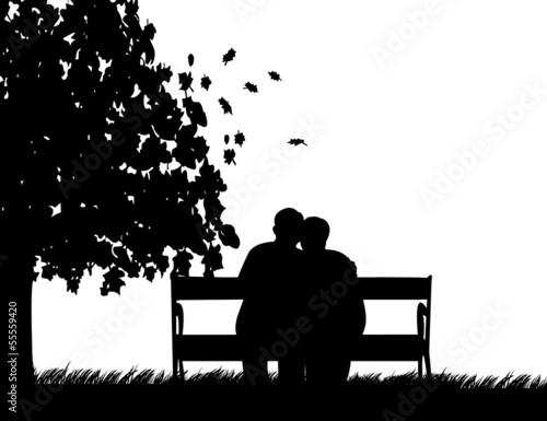 Retired elderly couple sitting on bench in park in fall