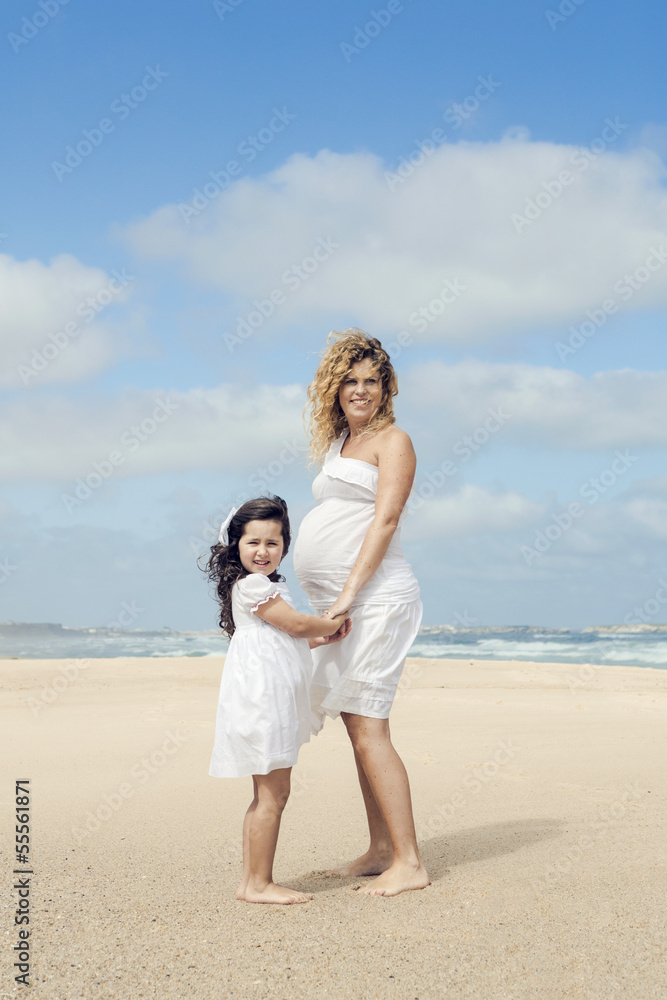 Pregnant woman and her daughter on the beach Pregnant woman and her daughter on the beach