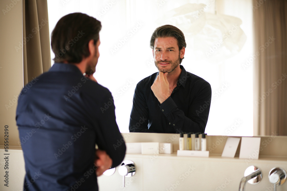 Mann betrachtet sich im Spiegel Stock Photo | Adobe Stock