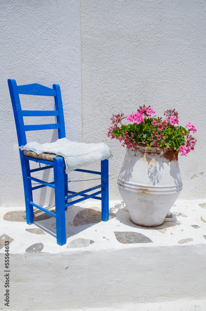 Traditional greek blue chair together with flowerpot