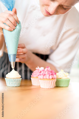 Woman decorating homemade cupcakes with cream