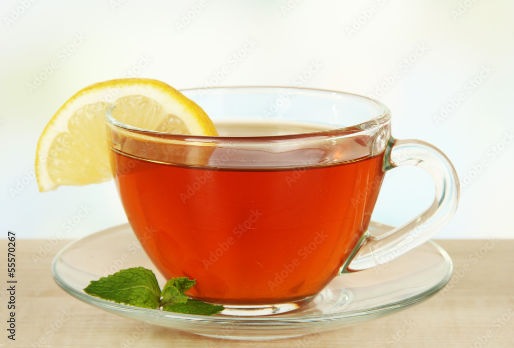Cup of tea with lemon on table on light background