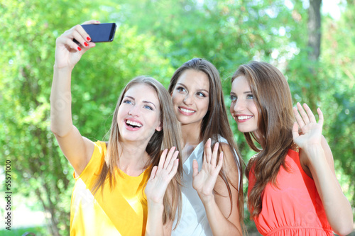 Three beautiful young woman taking picture in summer park