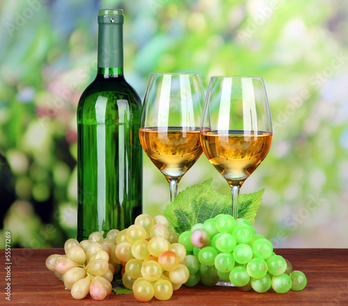 Ripe grapes, bottle and glasses of wine, on bright background