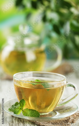 Cup of herbal tea with fresh mint flowers on wooden table