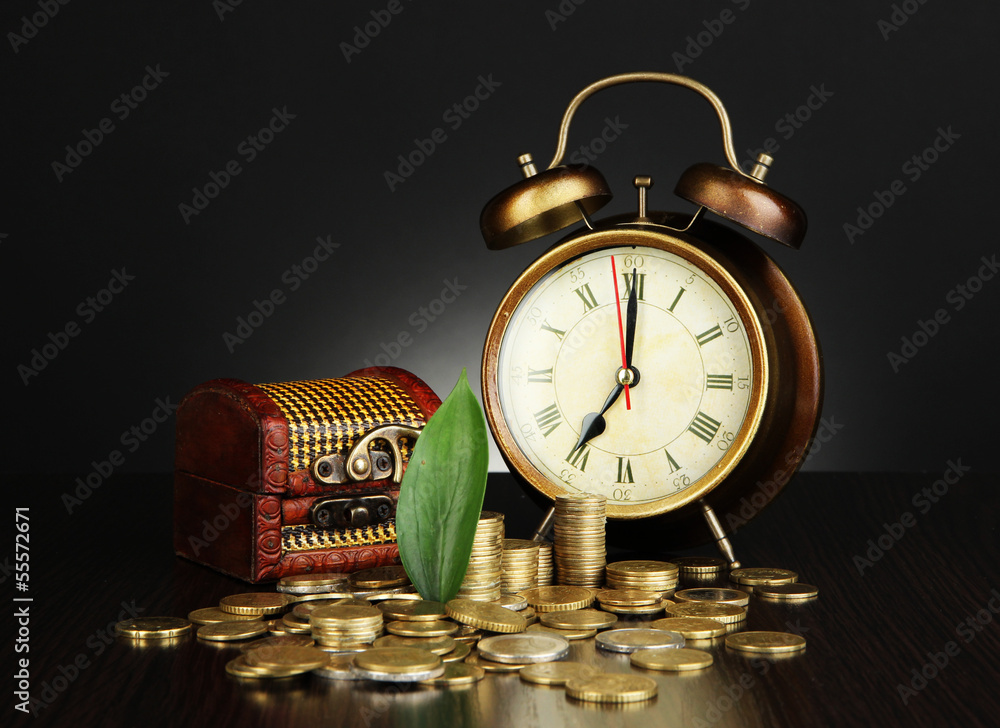 Antique clock and coins on wooden table on dark color Antique clock and coins on wooden table on dark color