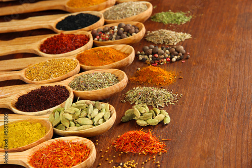 Assortment of spices in wooden spoons on wooden background