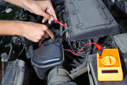 Auto mechanic uses multimeter voltmeter to check voltage level