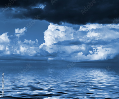 Sky with clouds reflected in water surface. Blue toned image.