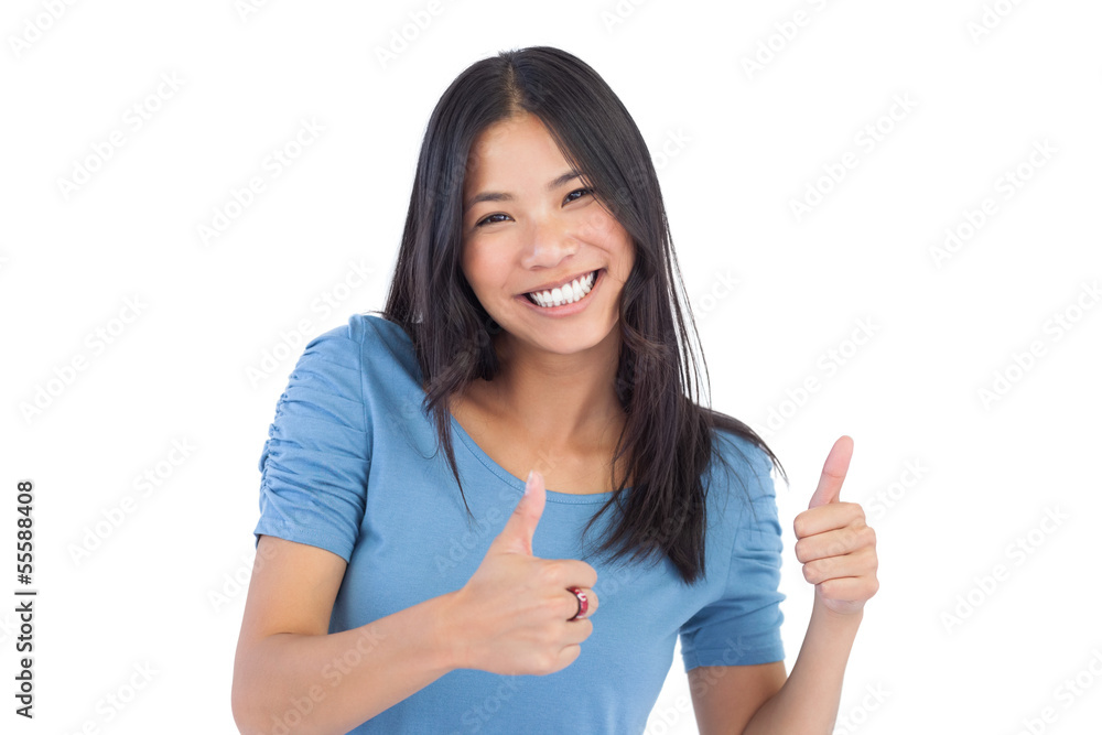 Smiling asian woman giving thumbs up at camera Smiling asian woman giving thumbs up at camera