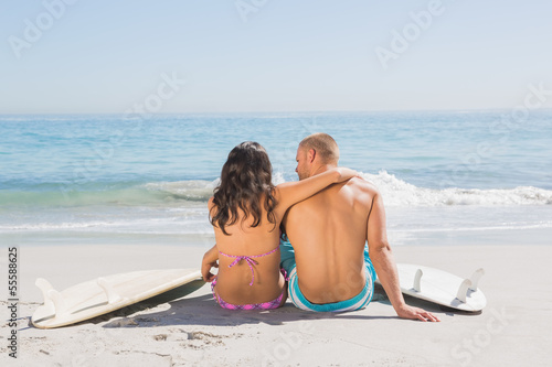 Pretty young couple sitting with their surfboards