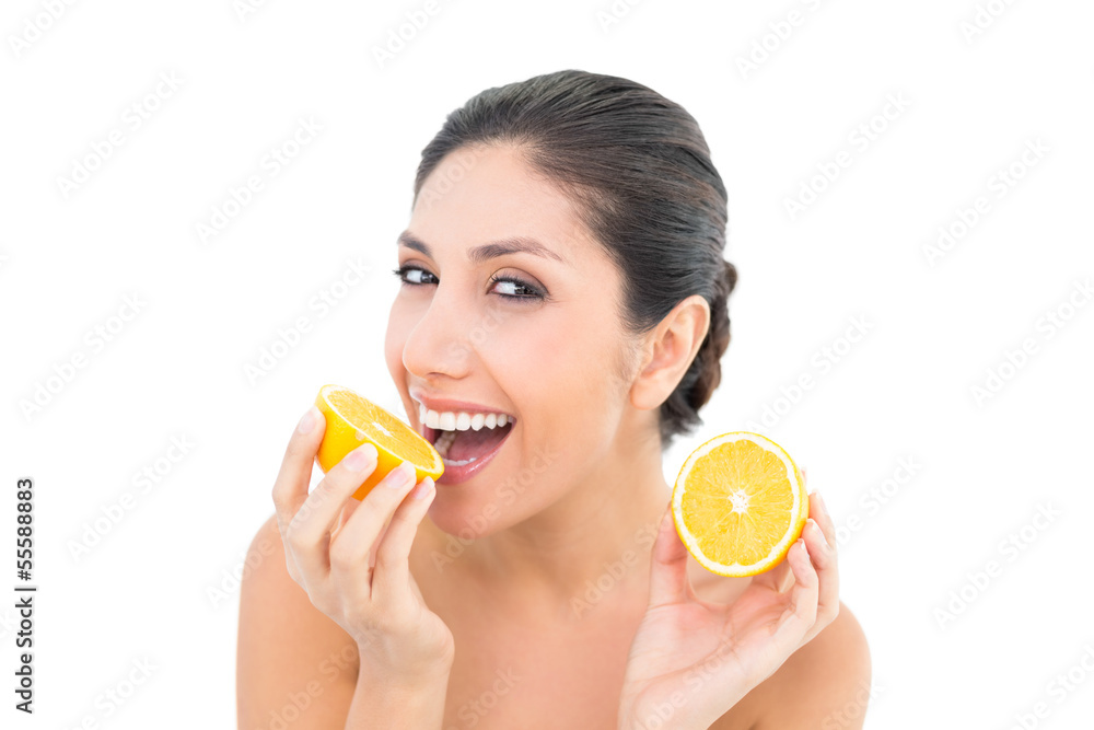 Pretty brunette holding two orange halves and smiling at camera Pretty brunette holding two orange halves and smiling at camera