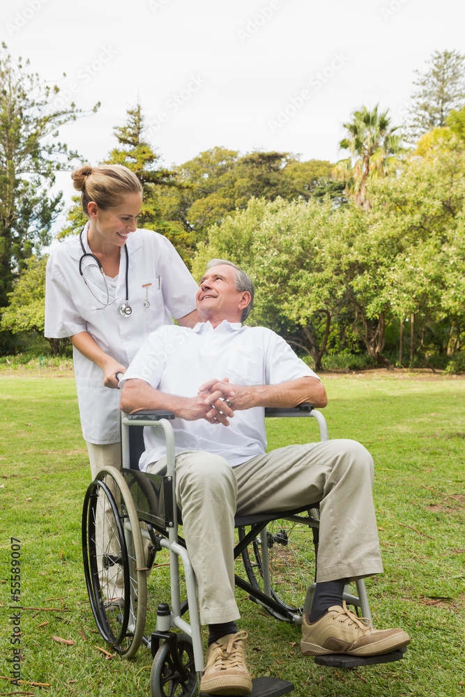 Happy man sitting in a wheelchair talking with his nurse pushing Happy man sitting in a wheelchair talking with his nurse pushing