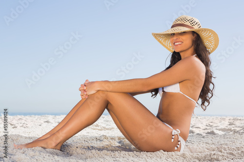 Attractive brunette in white bikini posing while sitting