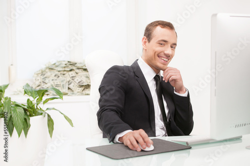 Successful businessman. Happy young businessman sitting at his w