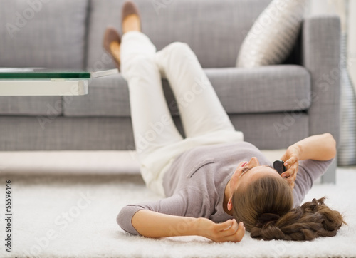 Young woman talking mobile phone while laying on floor
