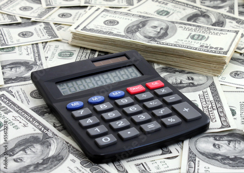 calculating income: calculator near a pile of dollars