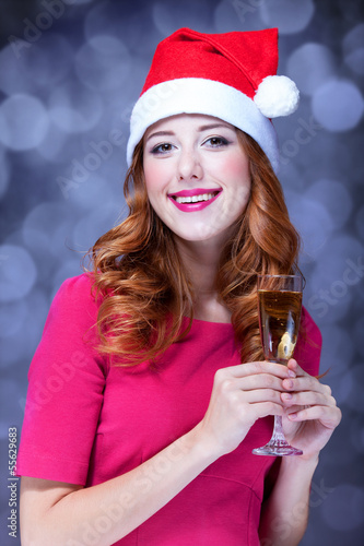 Redhead girl in christmas hat with champagne