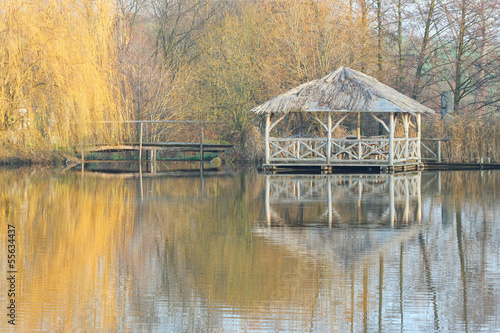 Wooden arbour in autumn by a lake with reflections