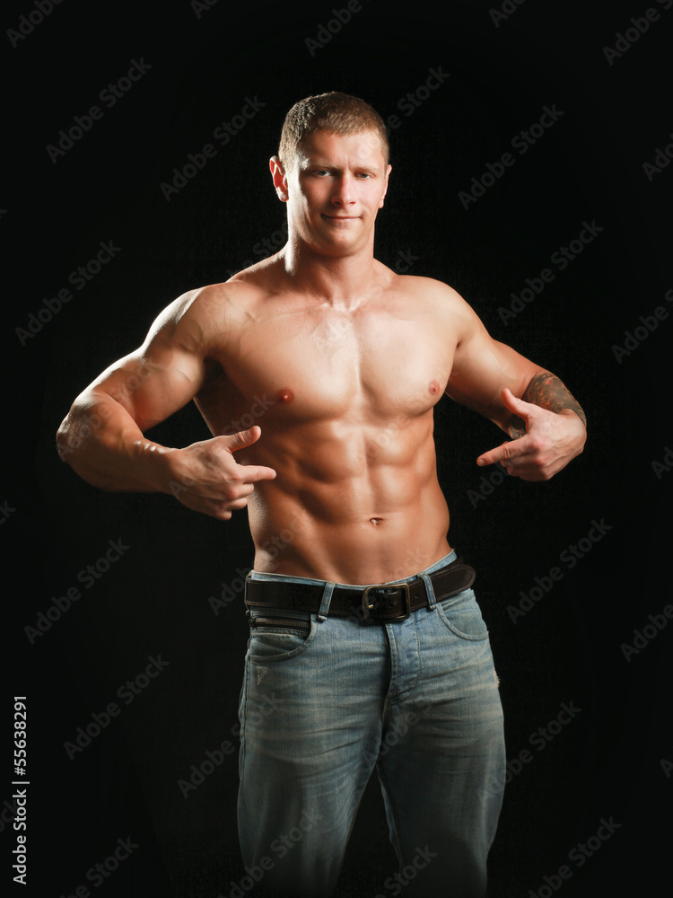 Fototapeta premium Muscular young man showing abs, isolated on black background