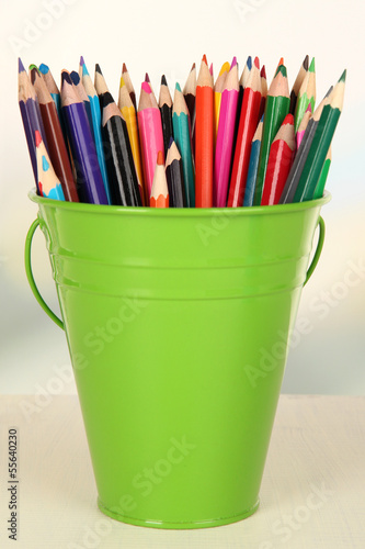 Color bucket with multicolor pencils, on color background