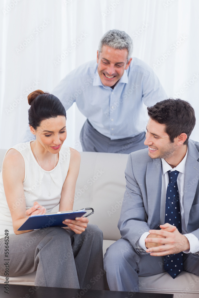 Woman signing a contract as husband and salesman are watching Woman signing a contract as husband and salesman are watching