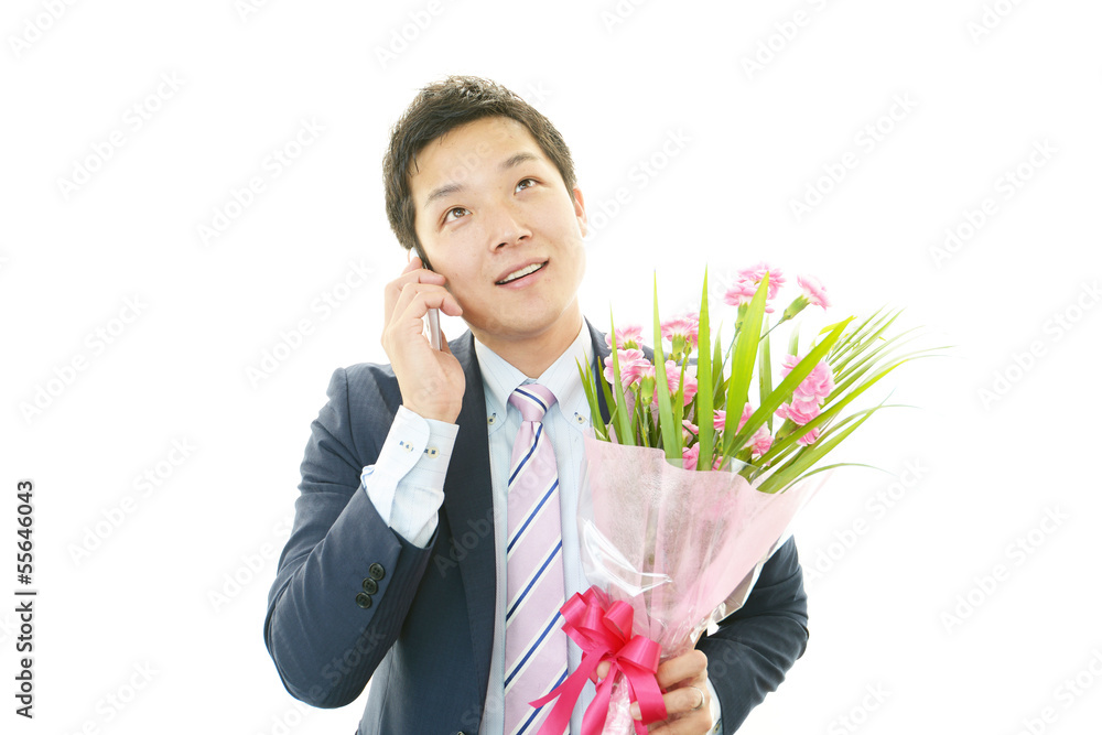 プレゼントの花束を持つ笑顔のビジネスマン