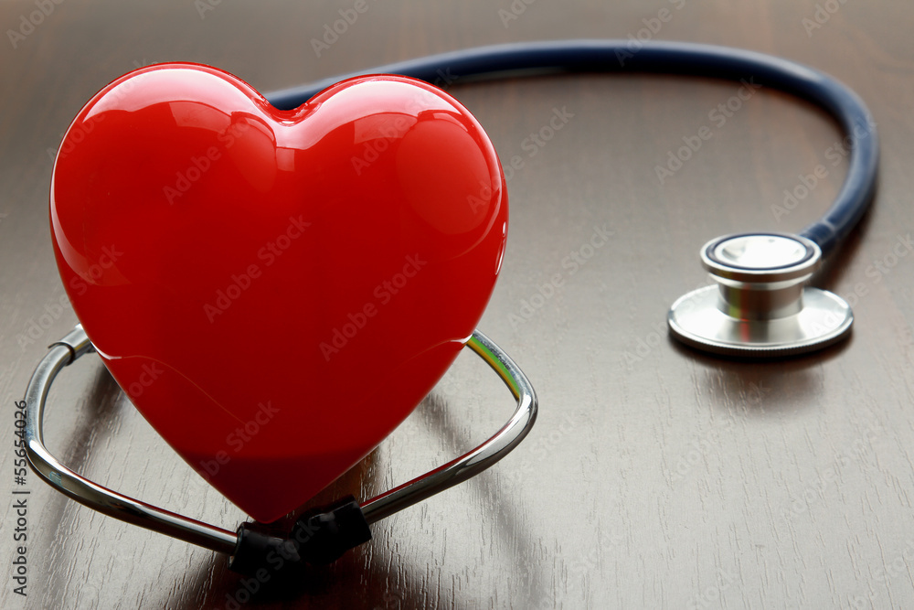 A heart with a stethoscope, isolated on wooden background A heart with a stethoscope, isolated on wooden background