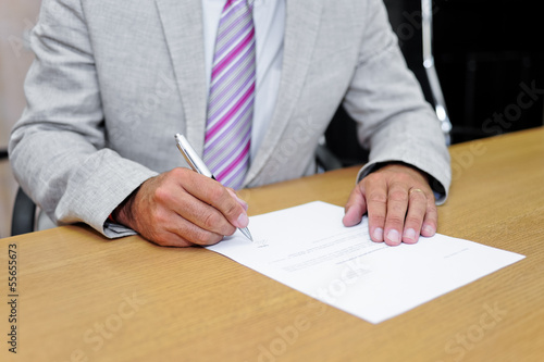 Uomo d'affari che firma un modulo cartaceo photo