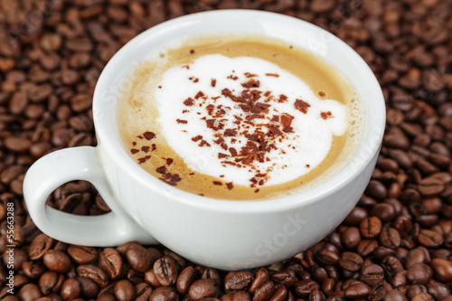 cappucino in cup on coffee beans