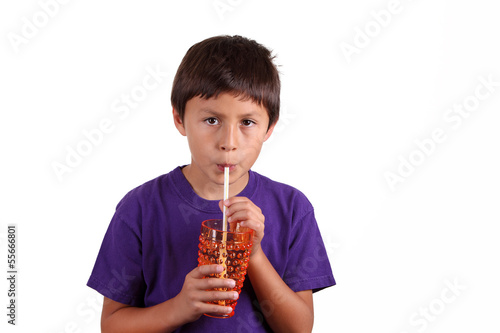 Young boy drinking from orange glass on white background