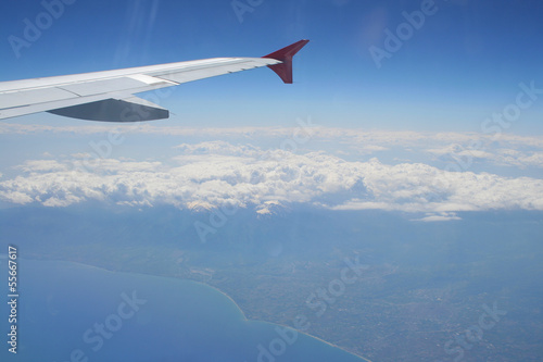 View of jet plane wing with land and sea below