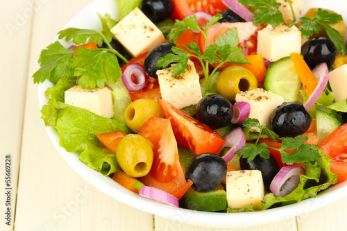 Fresh salad in plate on wooden table