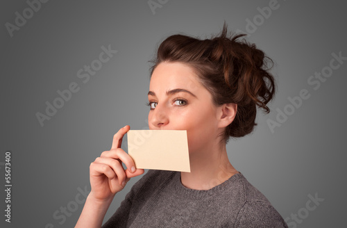 Cute girl holding white card at front of her lips with copy spac