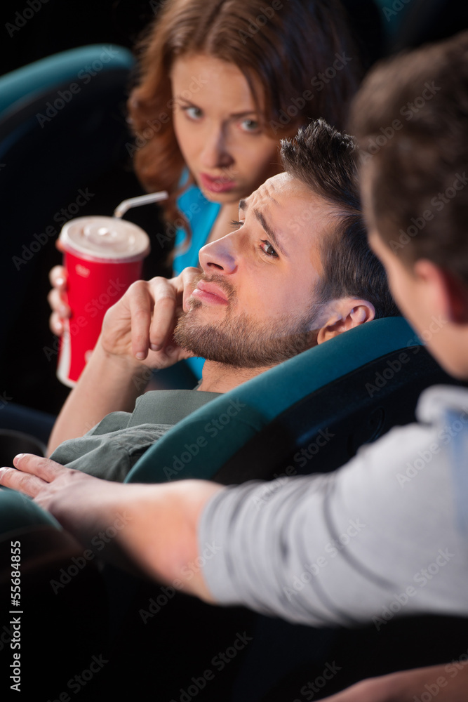 Talking at phone in cinema. Young men talking at phone while wat Talking at phone in cinema. Young men talking at phone while wat