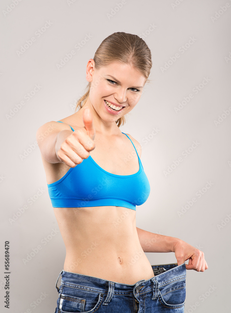 Loosing weight woman in big jeans showing thumb up Loosing weight woman in big jeans showing thumb up